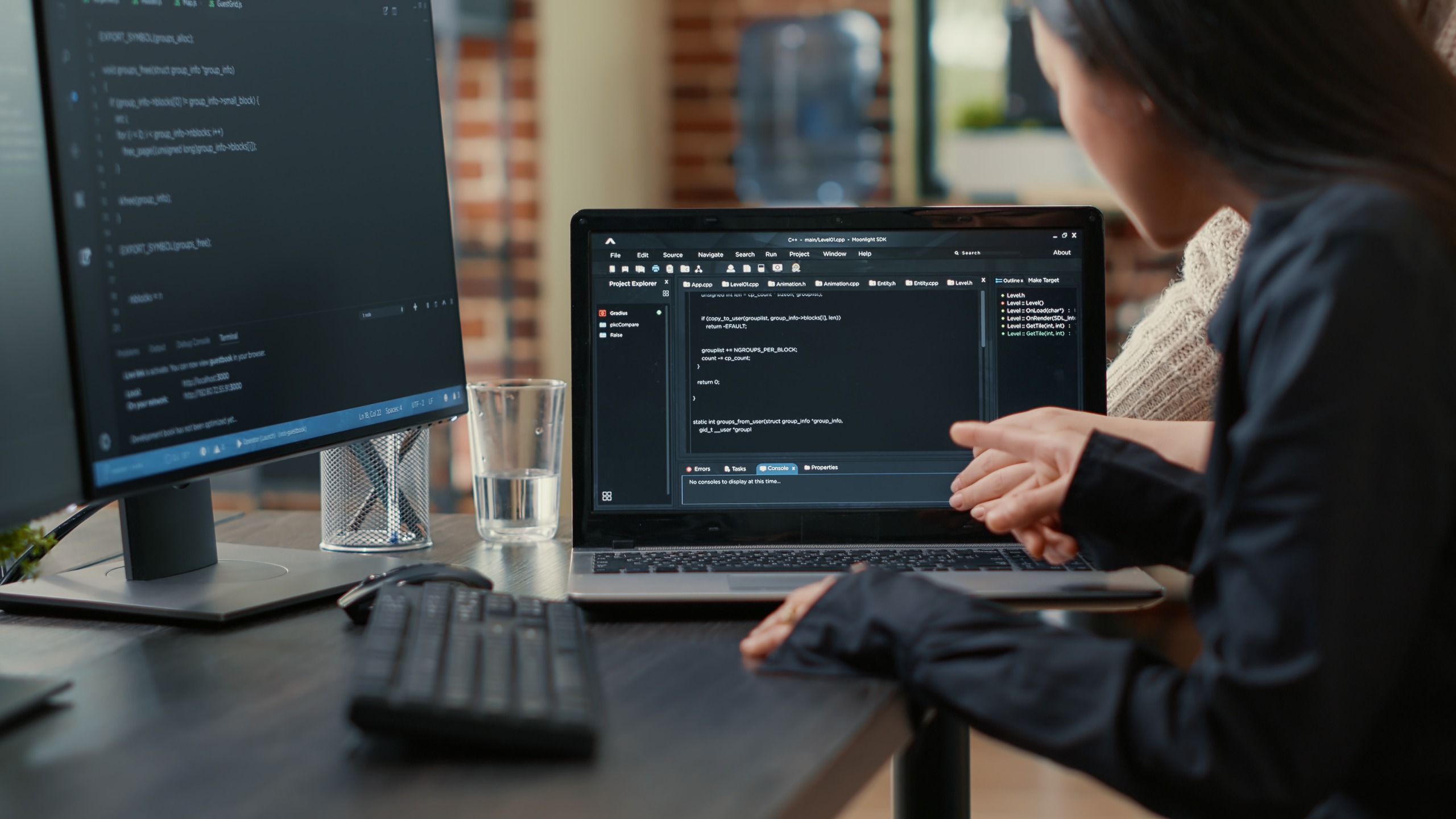 Developer reviewing custom software source code on a laptop and external monitor